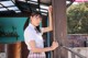 A woman in a school uniform leaning against a wooden door.