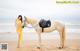 A woman in a yellow bikini standing next to a white horse.