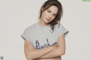 A woman with her arms crossed in front of a white background.