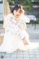 A woman in a white dress sitting on a bench.