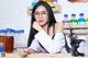 A woman in a lab coat and glasses sitting at a table.