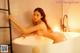 A naked woman sitting in a bathtub in a bathroom.