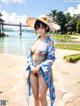 A woman in a blue kimono and a straw hat on a beach.