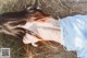 A woman in a white dress laying in the grass.