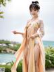 A woman in a yellow and orange kimono standing on a beach.