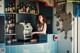 A woman sitting at a bar with a coffee machine.