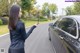 A woman standing next to a car holding a cell phone.