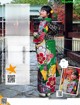 A woman in a colorful kimono standing in front of a gate.